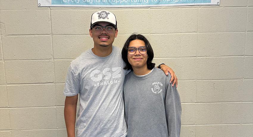 Two MCHS students posting in front of the Gallatin Shalom Zone flag